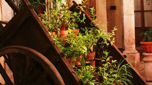 A wooden cart with potted plants, a wrought iron gate, and a building facade with columns and a door. - Hotel Alameda Centro Historico (Morelia)