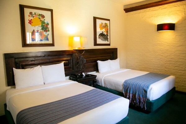 A hotel room with two beds, a nightstand, a lamp, and two framed floral artworks on the wall. - Hotel Alameda Centro Historico (Morelia)