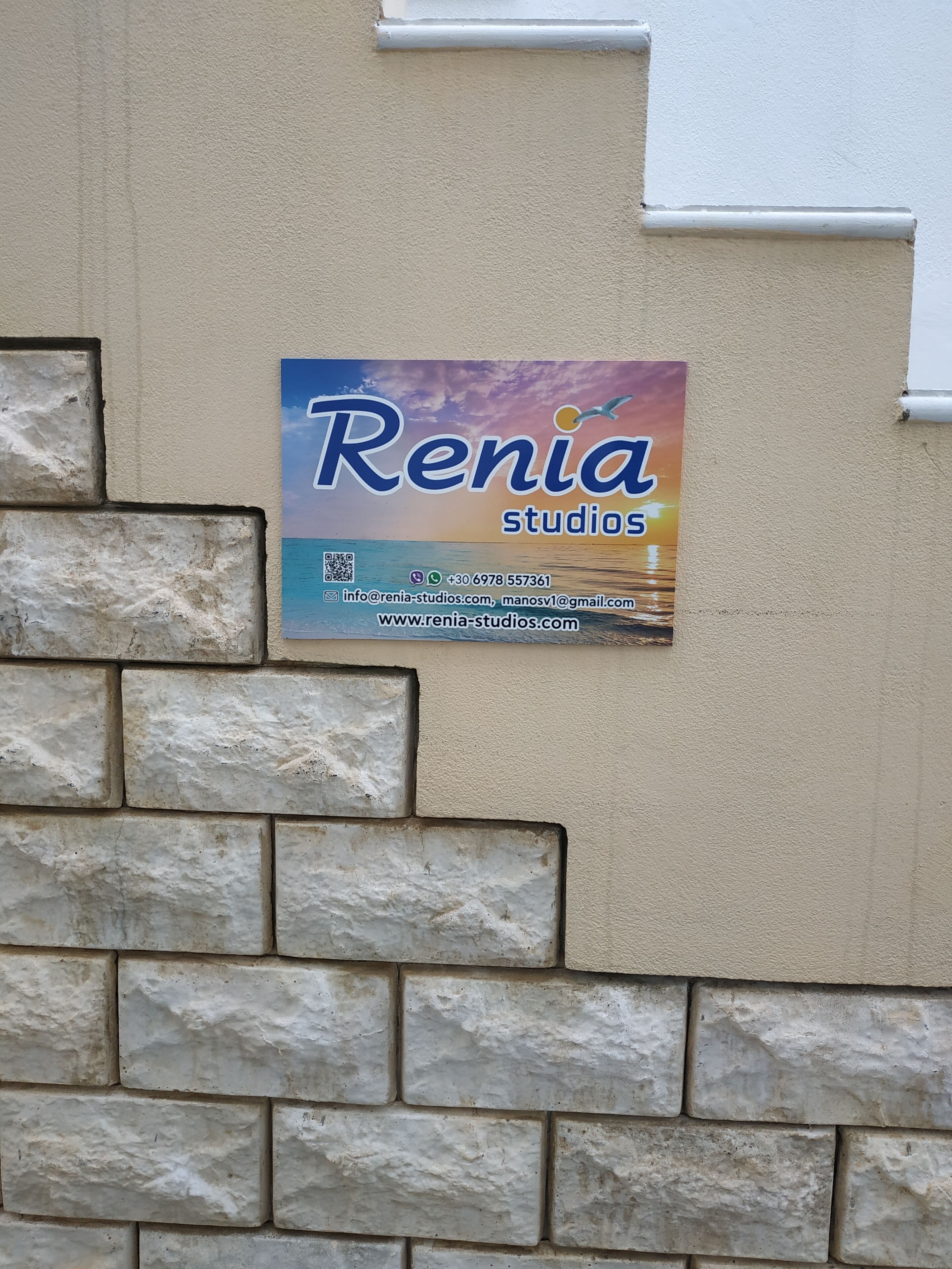 Letrero de Renia Studios sobre una pared color beige con base de piedra.