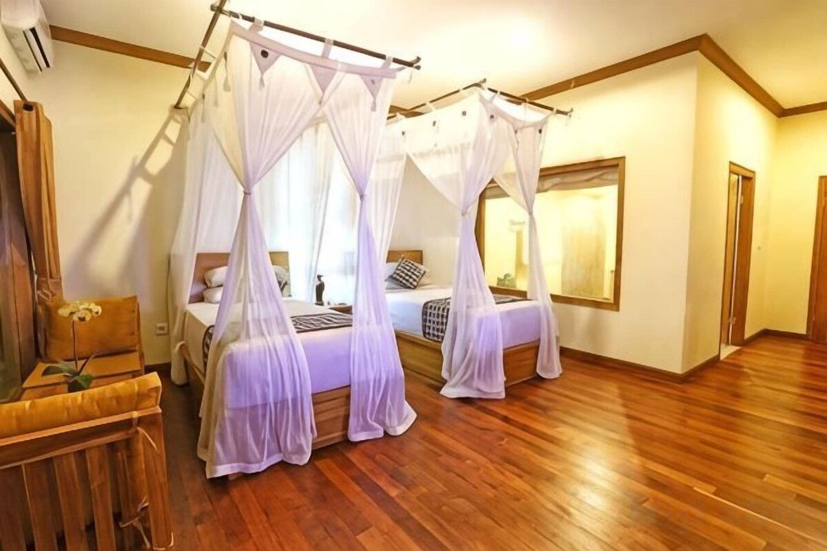 Un dormitorio con cama con dosel, suelo de madera y un espejo grande en la pared.