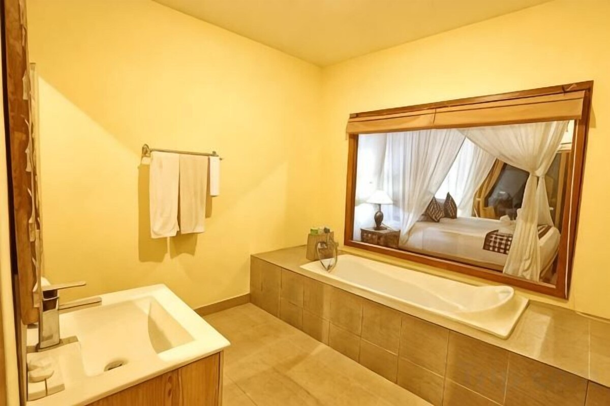 A bathroom with a bathtub, a sink, a mirror, and a towel rack.