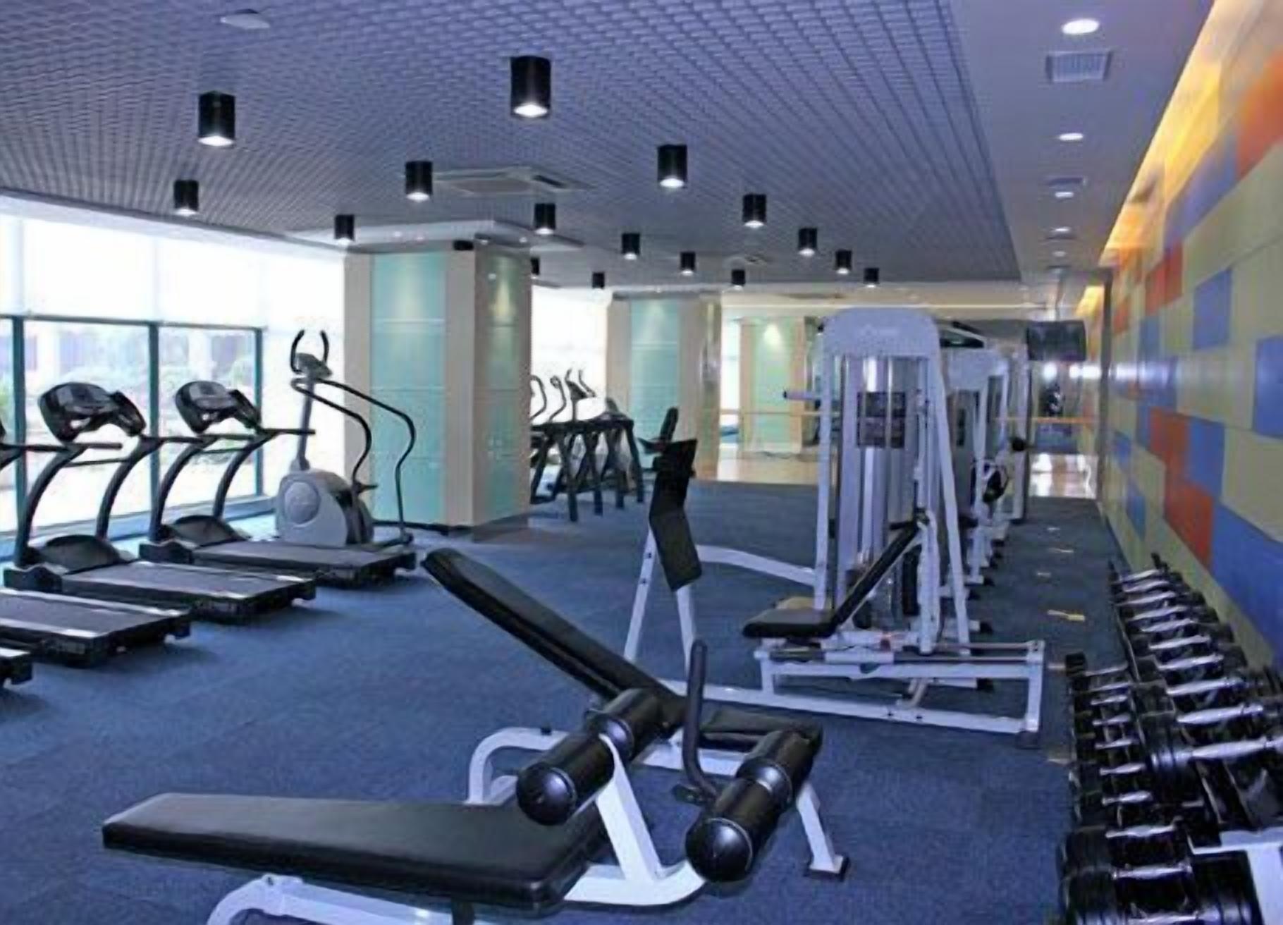 Un gimnasio con cintas de correr, máquinas de pesas y pesas sueltas.