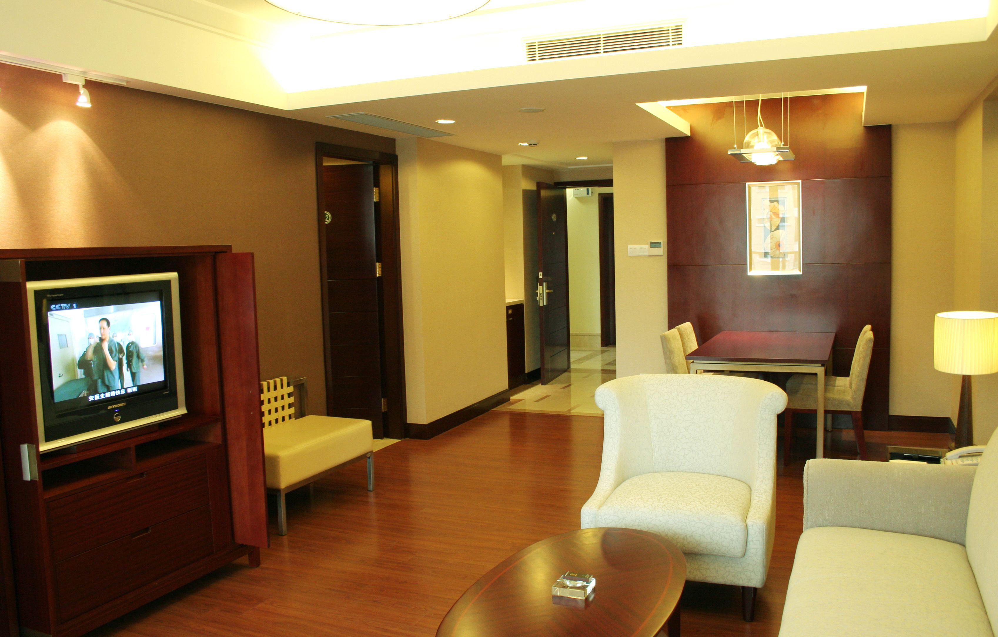 Habitación de hotel con televisión, zona de estar y mesa de comedor.