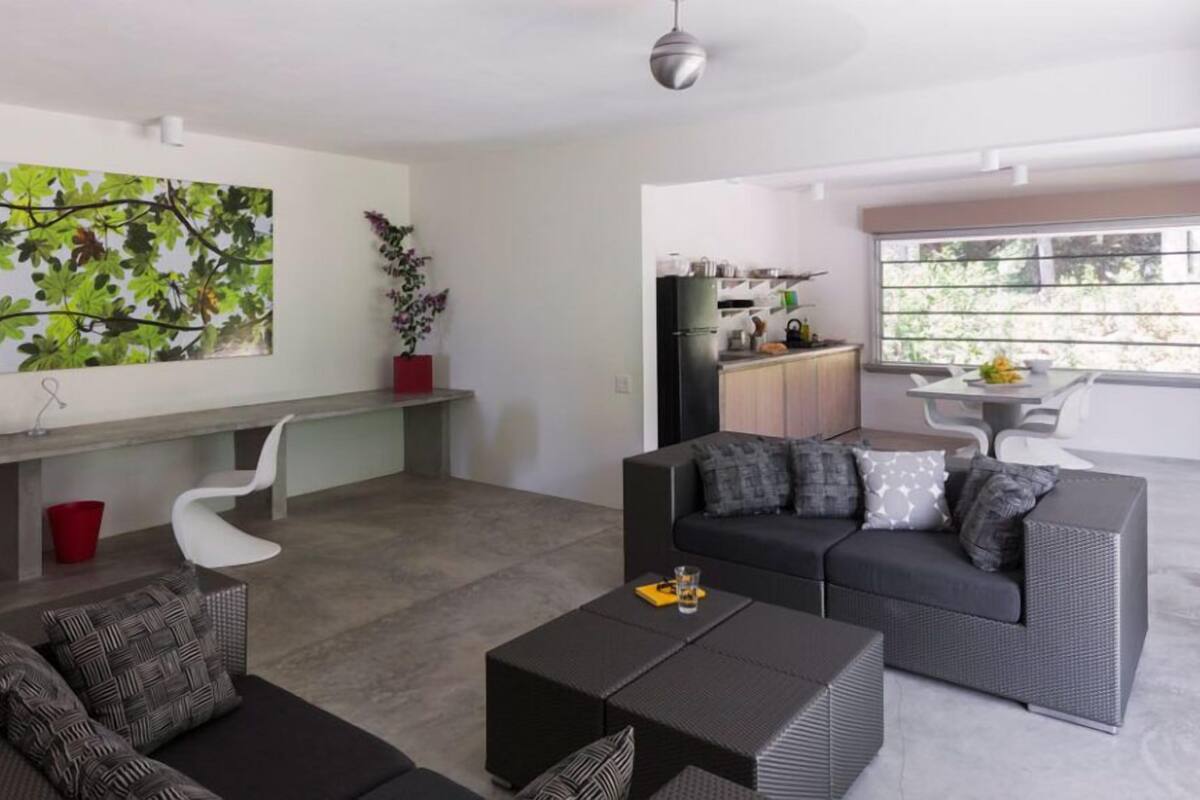 A modern living room with a sofa, coffee table, and a dining area with a table and chairs.