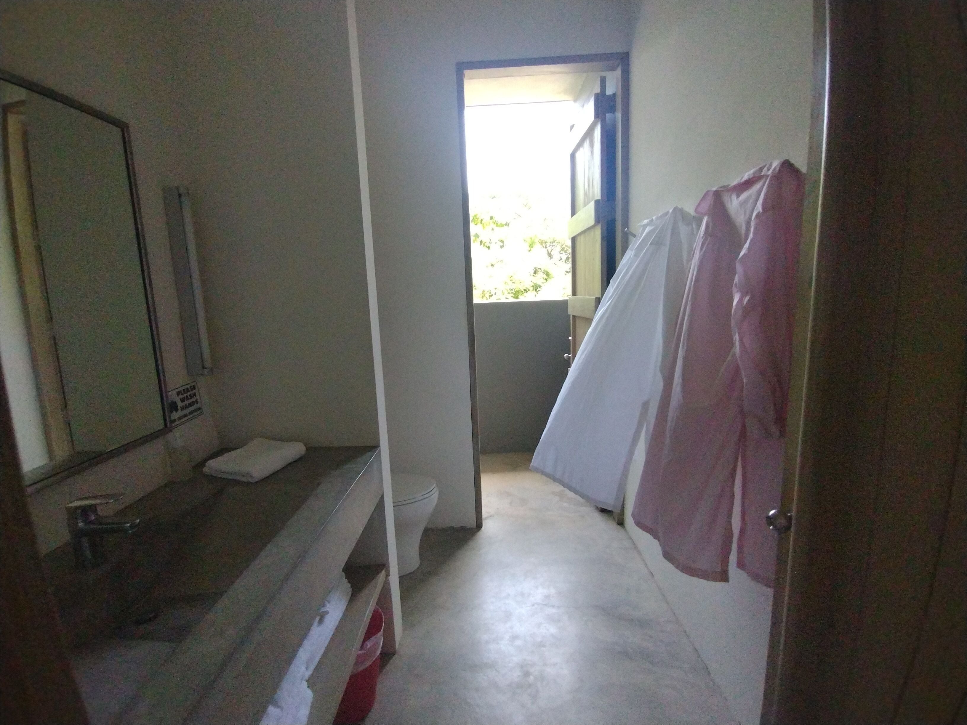 A narrow bathroom with a toilet, a sink, and a shower area.