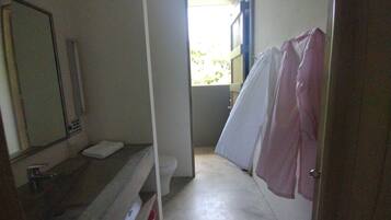 A narrow bathroom with a toilet, a sink, and a shower area.