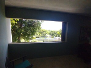 Enjoy a serene view of the lush landscape from the comfort of this room, featuring a large window and a simple layout.