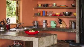 A kitchen with a concrete countertop, a red bowl, and various kitchen utensils.