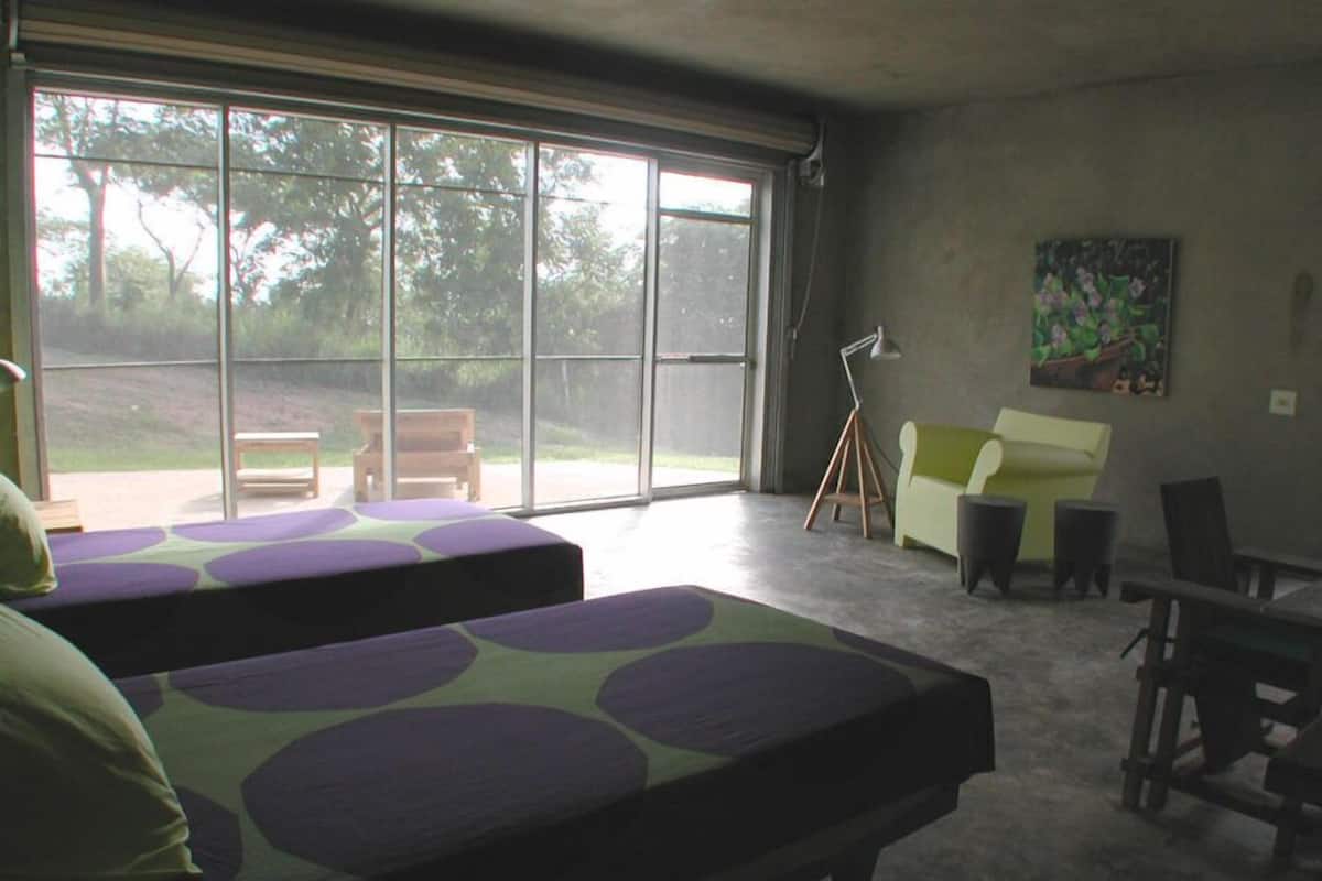 A room with two beds, a bench, a desk, and a chair.