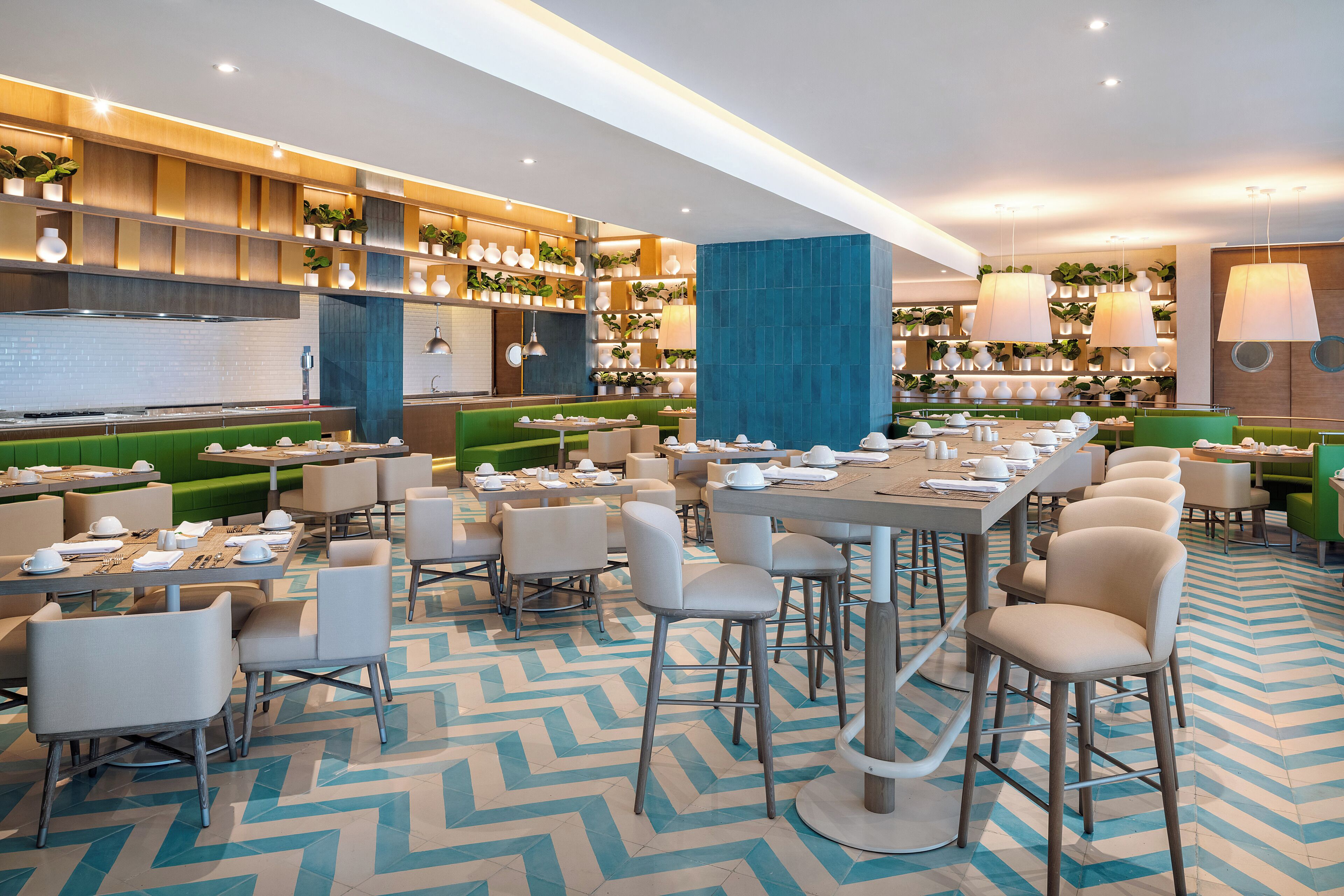 Un restaurante moderno con varias zonas de estar, incluyendo cabinas y mesas, y una cocina visible al fondo.