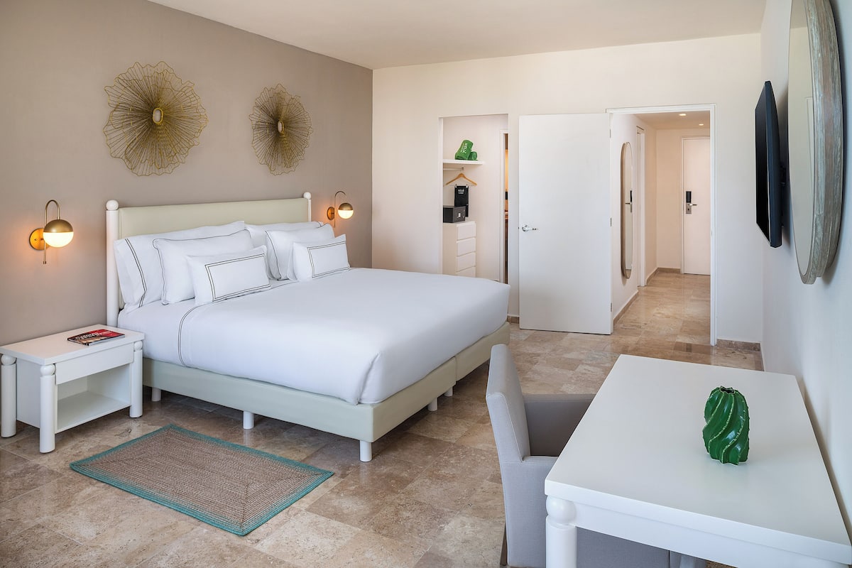 A hotel room with a bed, bedside tables, a desk, and a chair.