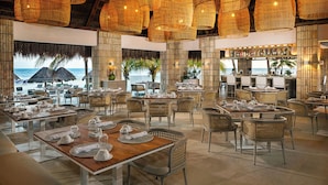 Un restaurante con mobiliario de mimbre, una zona de bar y vista al mar.