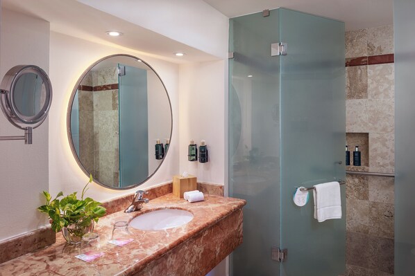 A bathroom with a marble sink, a round mirror, a glass shower enclosure, and a towel rack. - Meliá Casa Maya Cancún (Cancun)