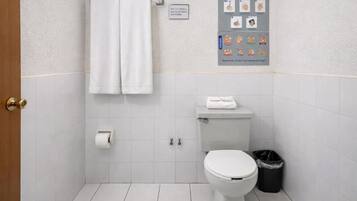 Un baño con inodoro, un cubo de basura y un cartel en la pared.