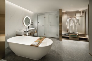 A modern bathroom with a freestanding bathtub, a round mirror, and a vanity with a sink.
