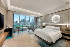 A modern hotel room with a large bed, a desk, a chair, a TV, and a city view. - Grand Skylight Garden Hotel Shenzhen (Shenzhen)