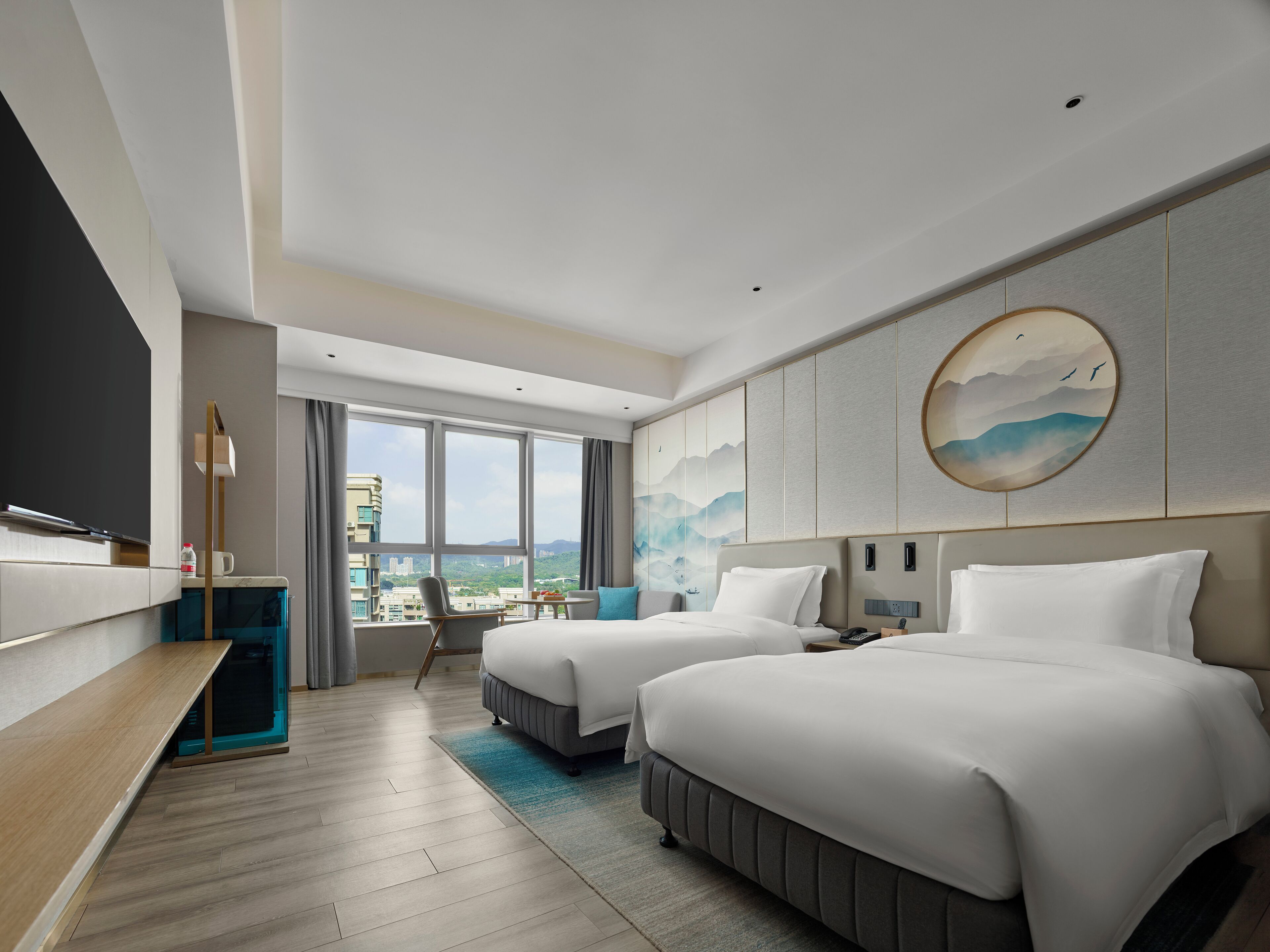 Una habitación de hotel moderna con dos camas, un escritorio, una silla y un amplio ventanal con vistas a la ciudad.