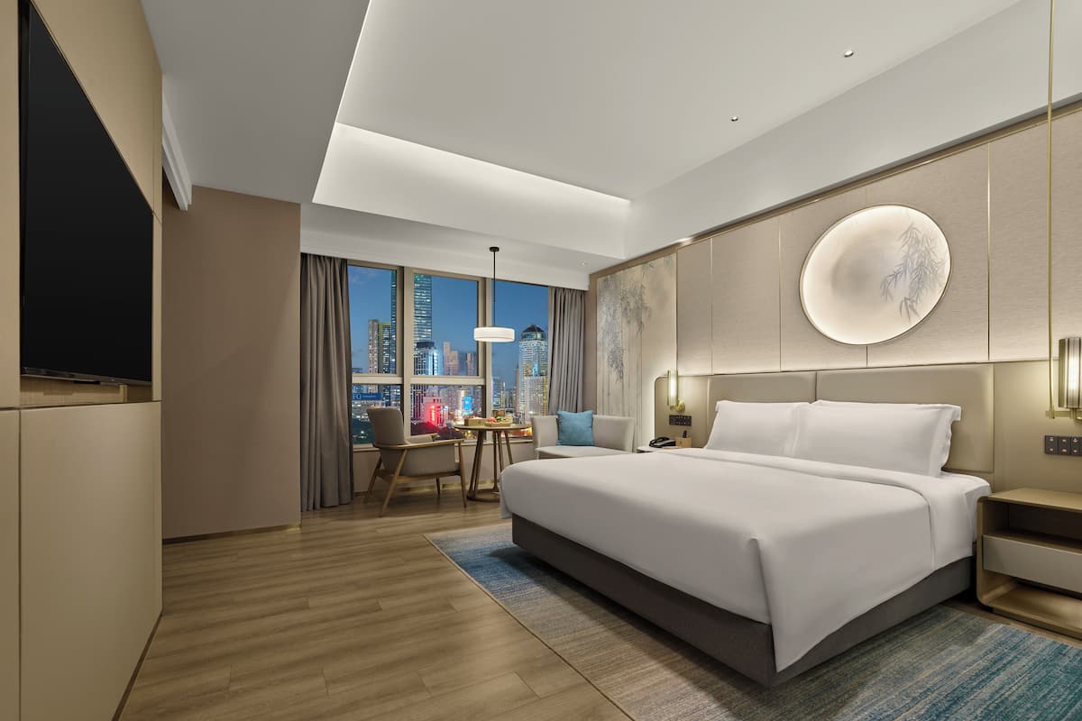 Une chambre d’hôtel moderne dotée d’un grand lit, d’un bureau et offrant une vue sur la ville.
