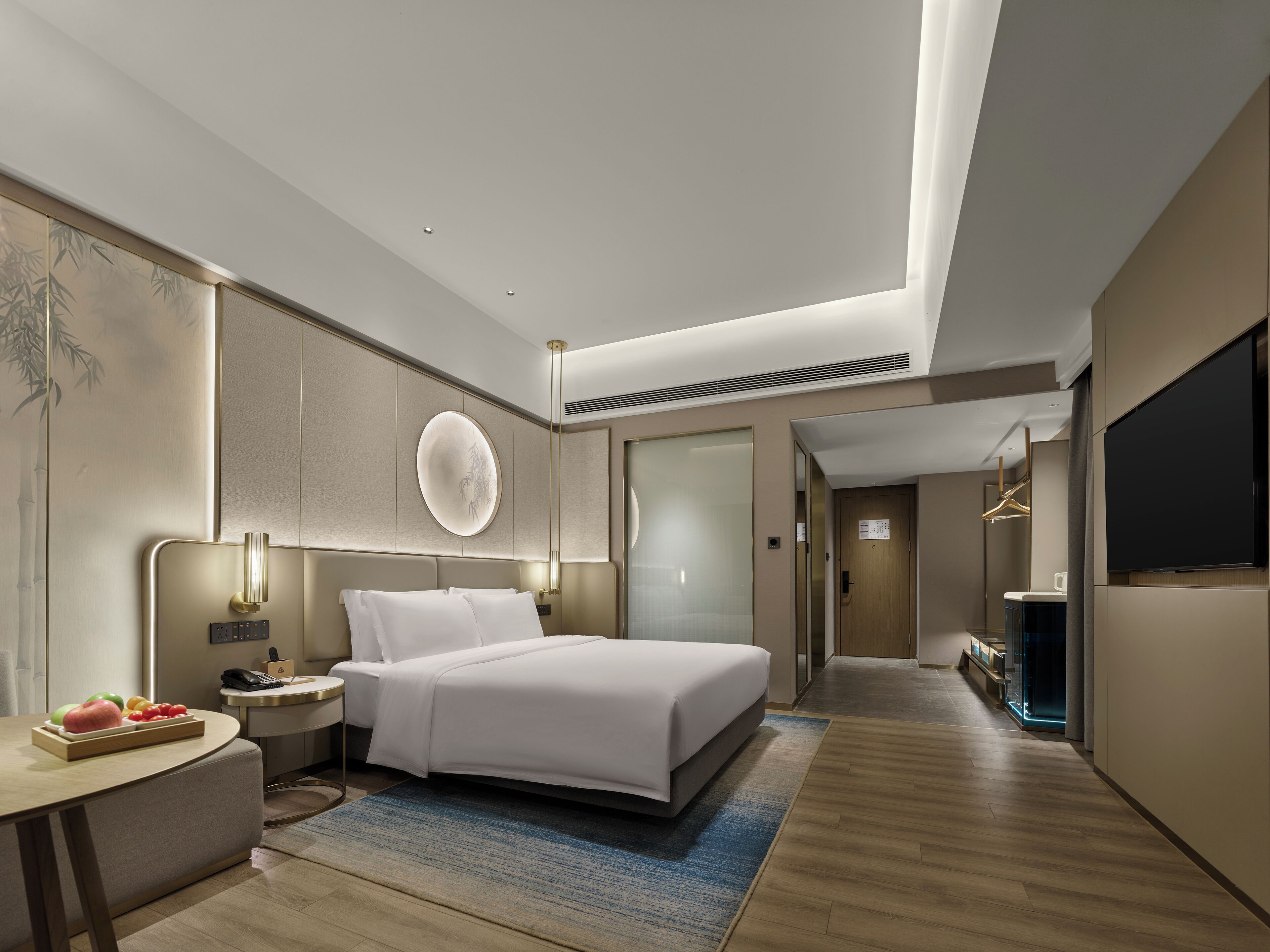 A modern hotel room with a large bed, bedside tables, a flat-screen TV, and a bathroom with a glass shower.