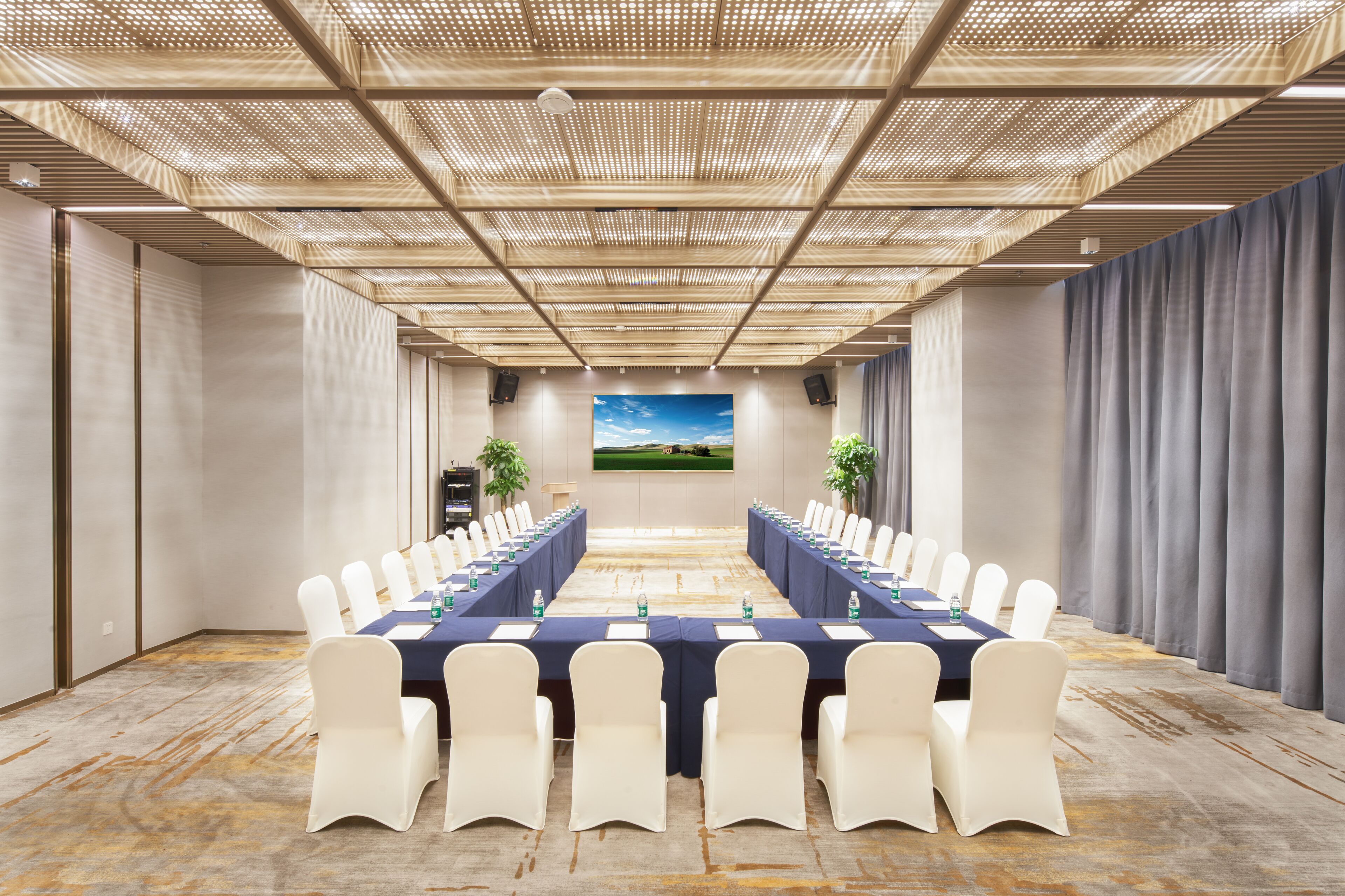 A conference room with a long table, white chairs, and a large window with a landscape view.