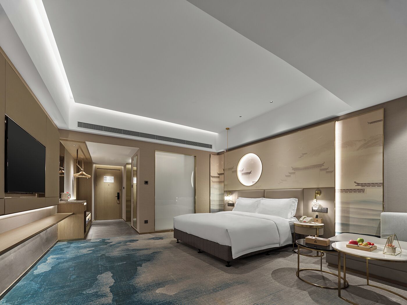 A modern hotel room with a large bed, bedside tables, a TV, and a bathroom visible through an open door.