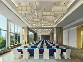 A conference room with tables and chairs, large windows, and a city view.