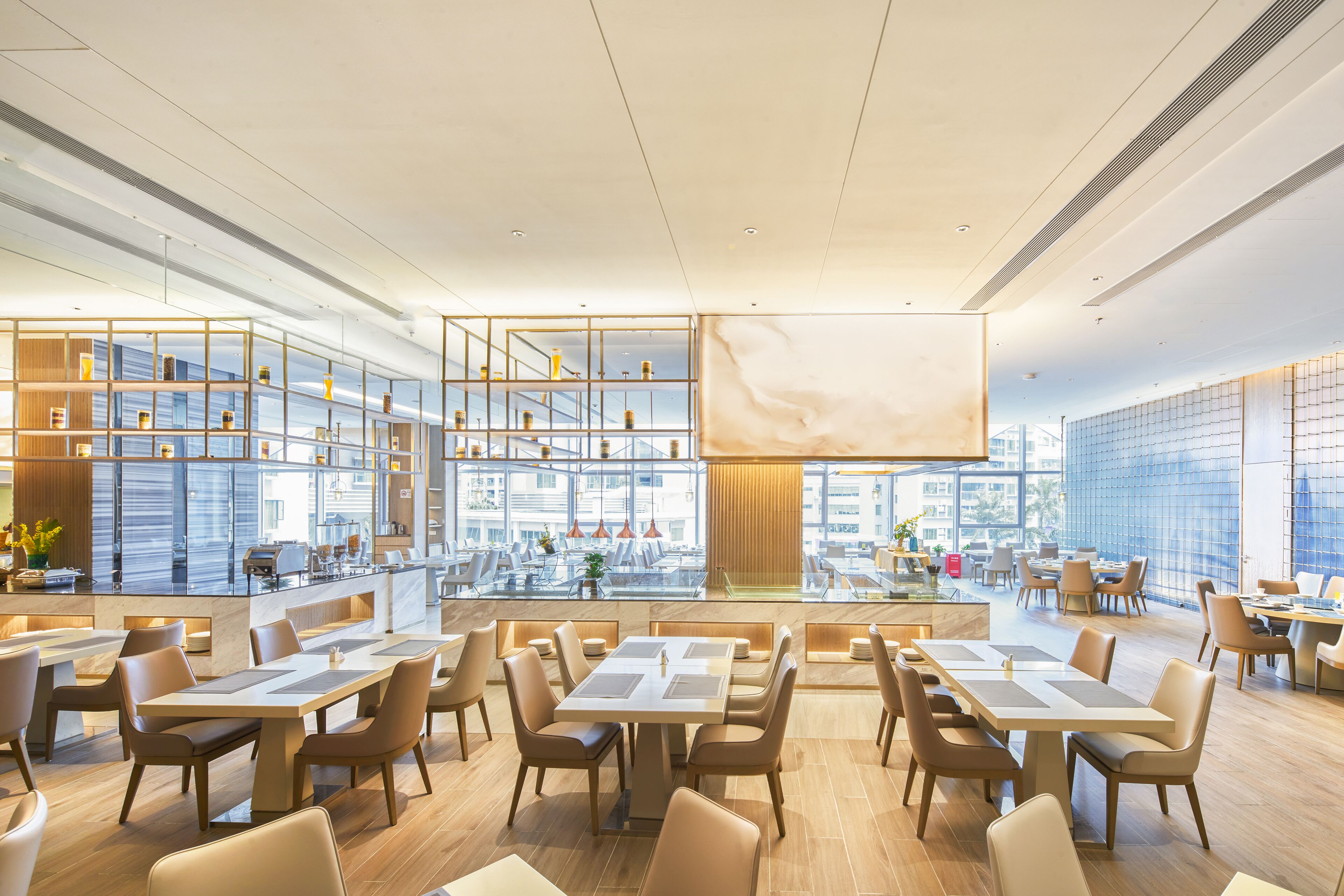 Ein geräumiges Restaurant mit hohen Decken, moderner Einrichtung und großen Fenstern mit Blick auf die Stadt.