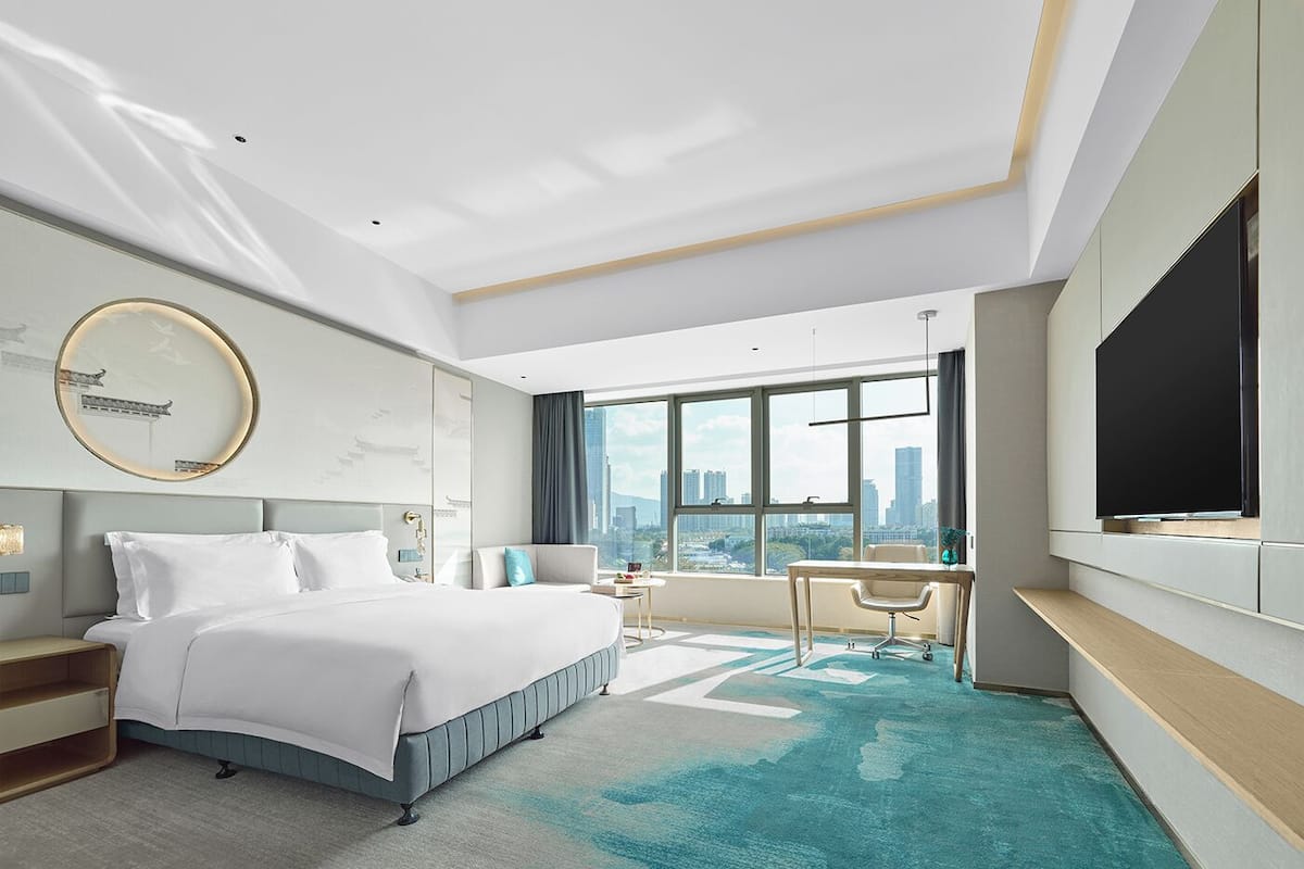 Une chambre d’hôtel moderne, dotée d’un grand lit, d’un bureau et d’une télévision.