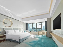 A modern hotel room with a large bed, a desk, and a TV.