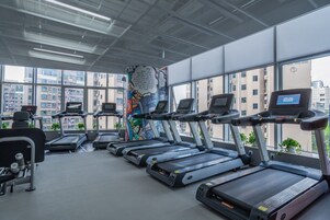 Un gimnasio con cintas de correr, bicicletas estáticas y pesas.