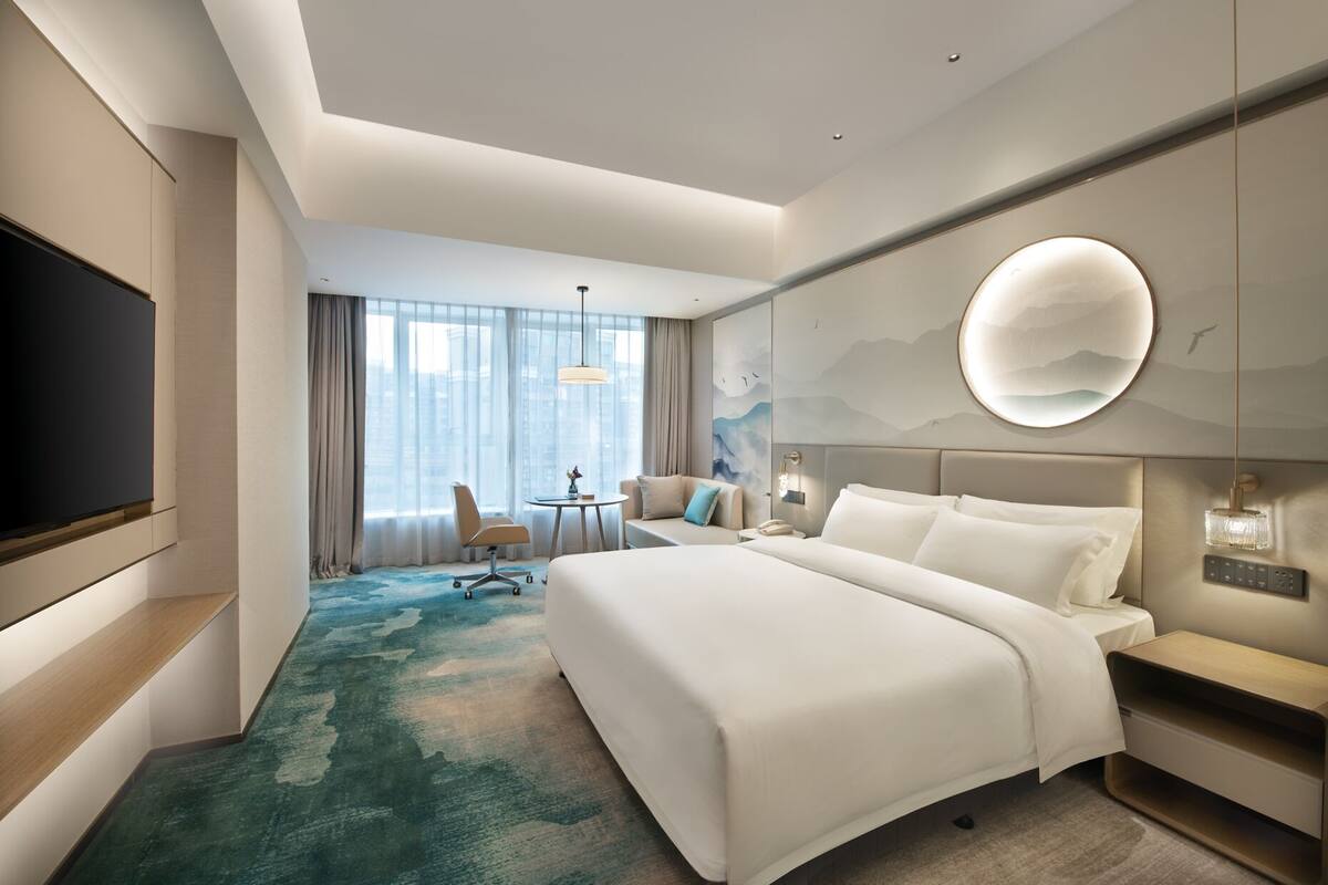 Une chambre d’hôtel moderne équipée d’un grand lit, d’un bureau, d’une chaise et d’une télévision.