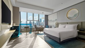 Een moderne hotelkamer met een groot bed, een bureau en uitzicht op de skyline van de stad.