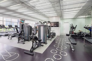 A gym with treadmills, weight machines, and a large window with a city view.