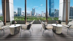 Een terras op het dak met rieten meubilair en uitzicht over de stad.