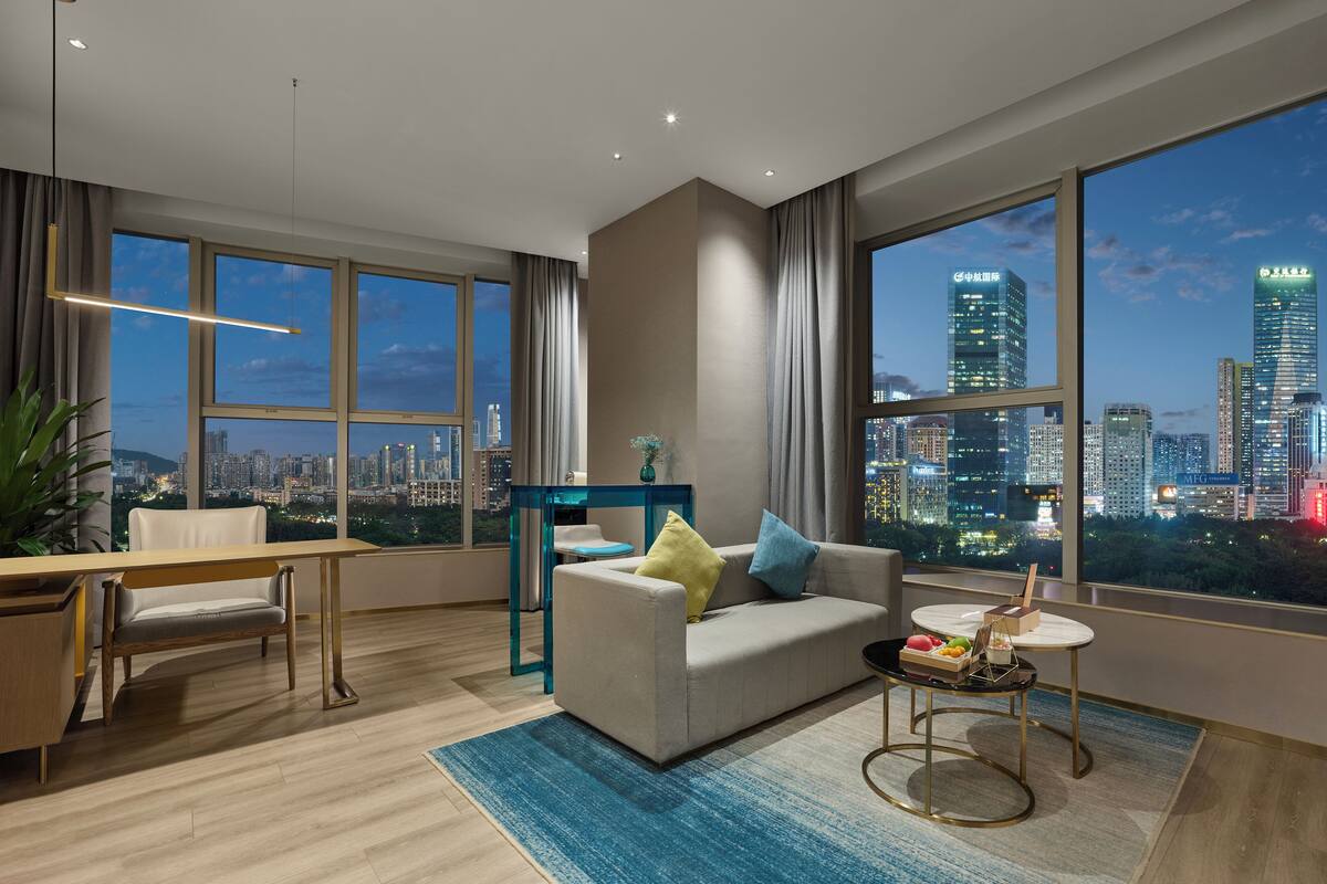 Un salon moderne avec vue sur la ville, un coin repas et un canapé agrémenté de coussins.