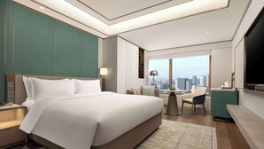 A modern hotel room with a large bed, a desk, a chair, and a view of the city skyline. - Wyndham Hangzhou Linping (Hangzhou)