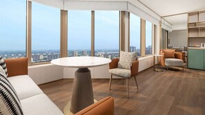A modern interior with a round table, orange seating, and large windows offering a city view. - Wyndham Hangzhou Linping (Hangzhou)