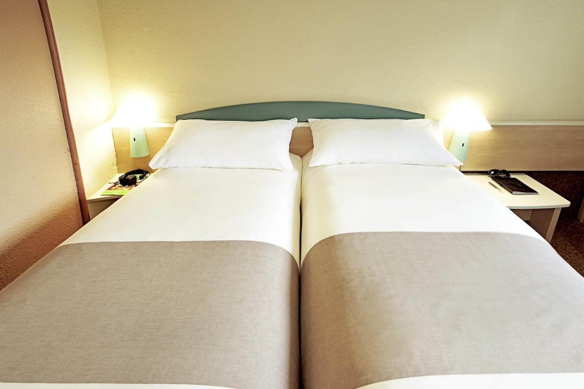 Una cama doble con dos mesitas de noche, cada una con una lámpara y un teléfono.