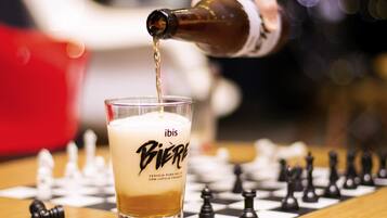 A glass of beer with a label, a chessboard, and chess pieces.