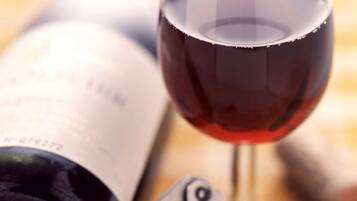A wine bottle and a wine glass with a corkscrew.