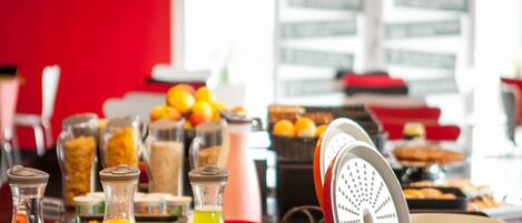 A breakfast buffet with various food items and drinks, including orange juice and a green smoothie.