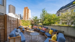 Una terrazza sul tetto con mobili da esterno, vista su un edificio alto e una recinzione in legno.