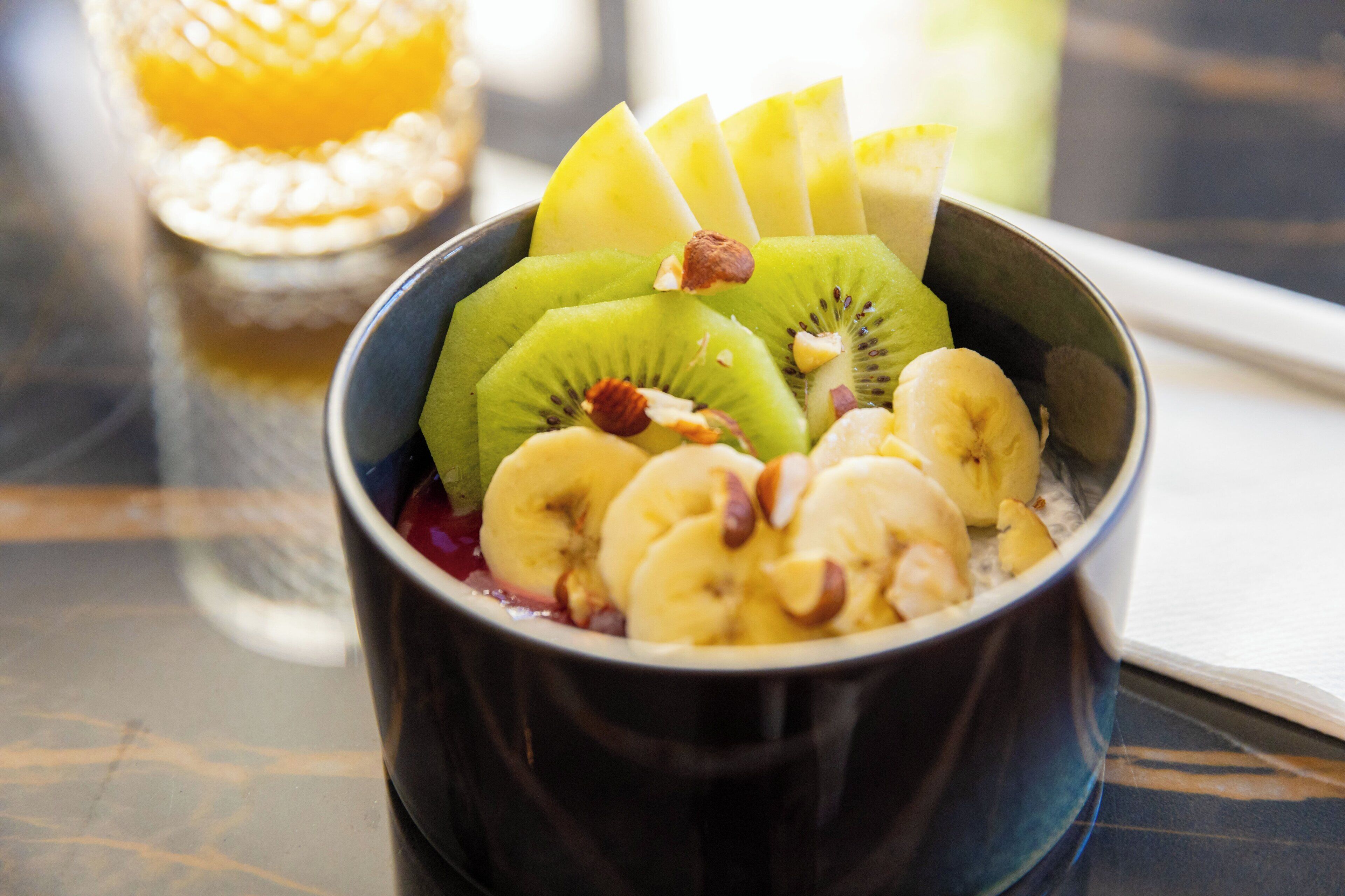 A bowl of fruit salad with bananas, kiwi, and nuts.