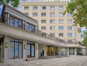 Un hotel con fachada moderna, varios pisos y una entrada destacada con puerta giratoria.