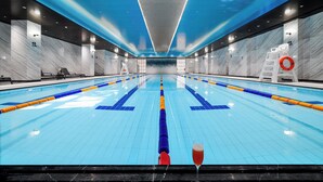A large indoor swimming pool with clear lane markings, a lifebuoy, and a glass of red drink on the edge. - Donghu Collection Hotel Shanghai (Shanghai)