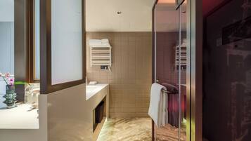 A modern bathroom with a marble floor, a glass shower enclosure, and a vanity with a towel rack.