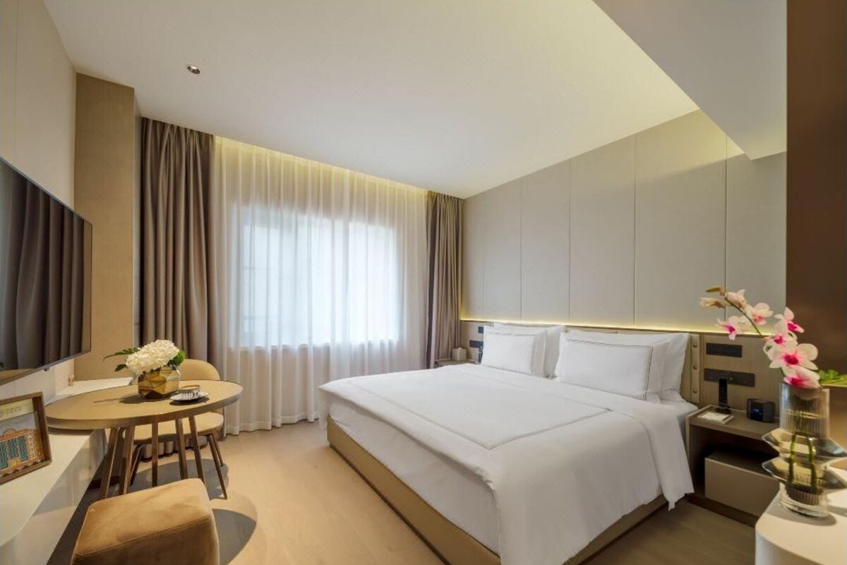 A modern hotel room with a large bed, a desk, and a chair.