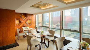 A modern dining area with patterned chairs and tables, large windows with city views, and a decorative ceiling. - Paramount Gallery Hotel (Shanghai)