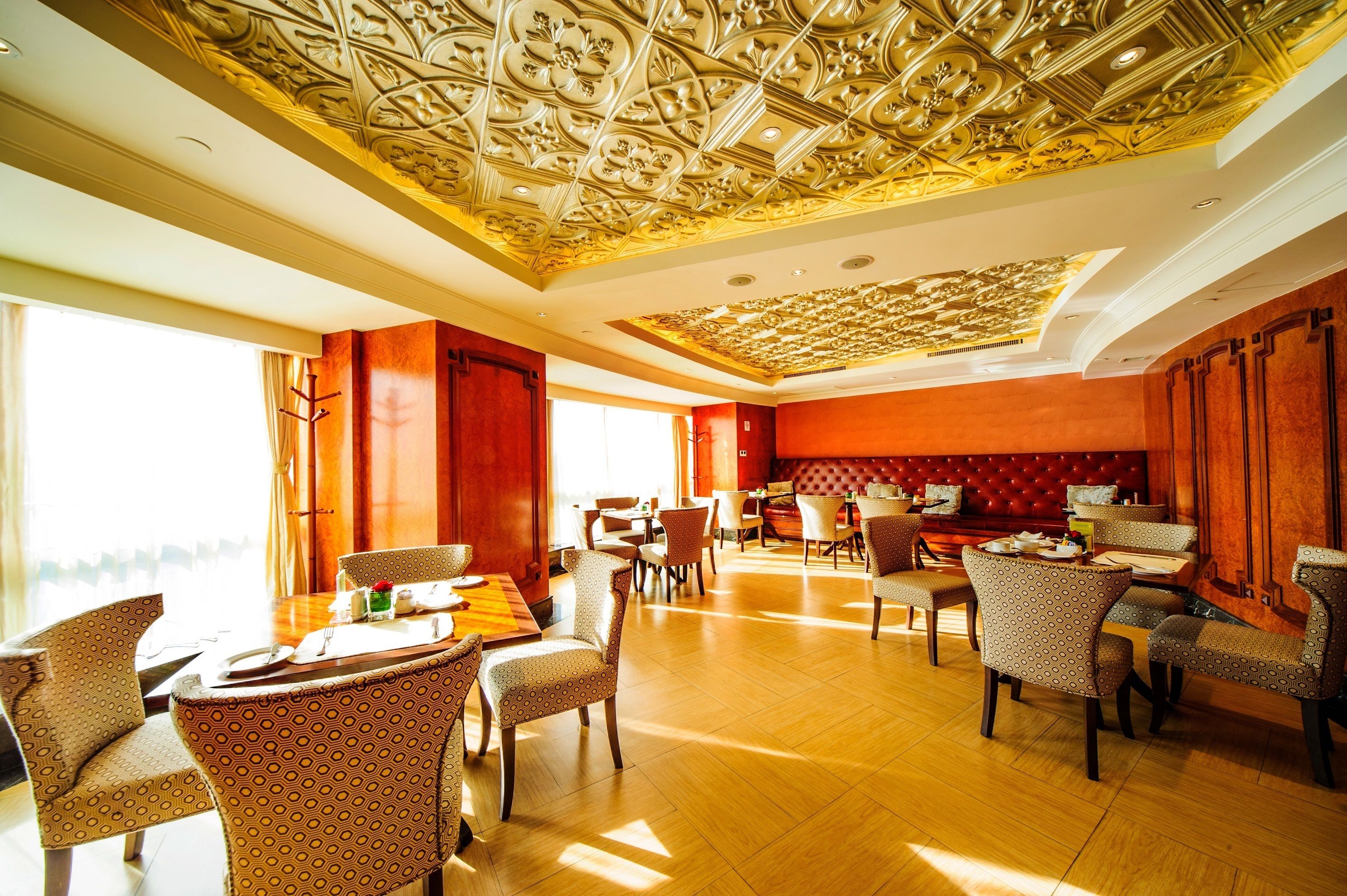 A spacious dining area with patterned chairs and a high ceiling with intricate designs.