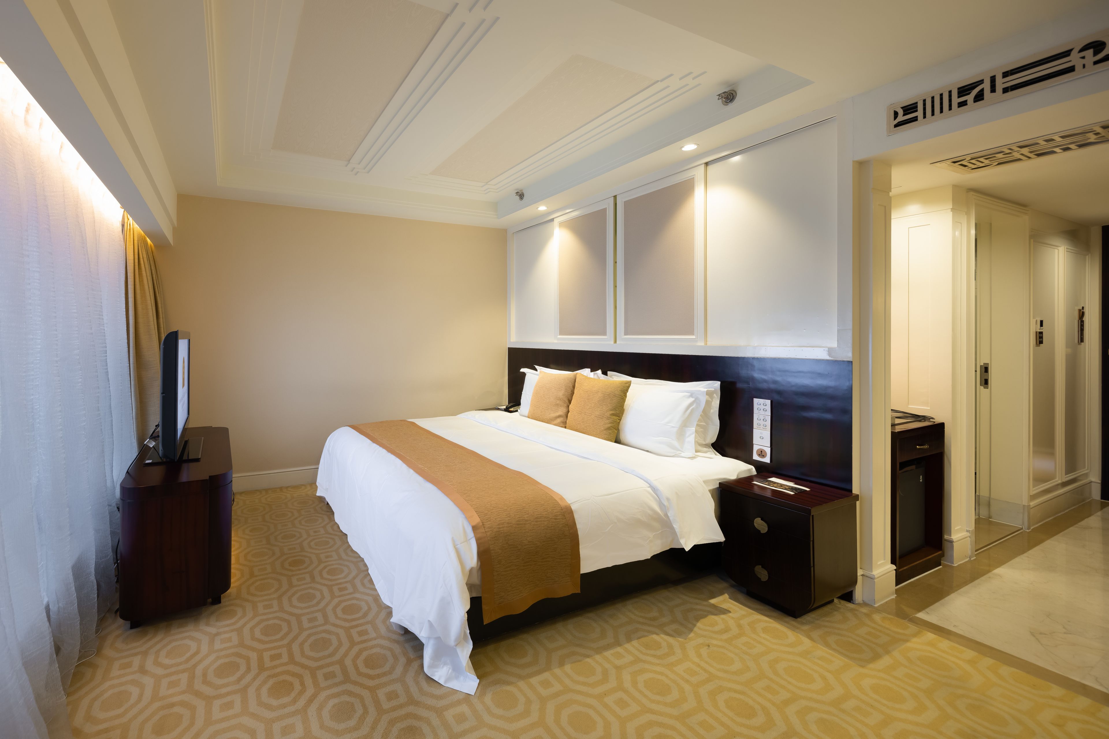 Een hotelkamer met een groot bed, een televisie, een dressoir en een kledingkast.